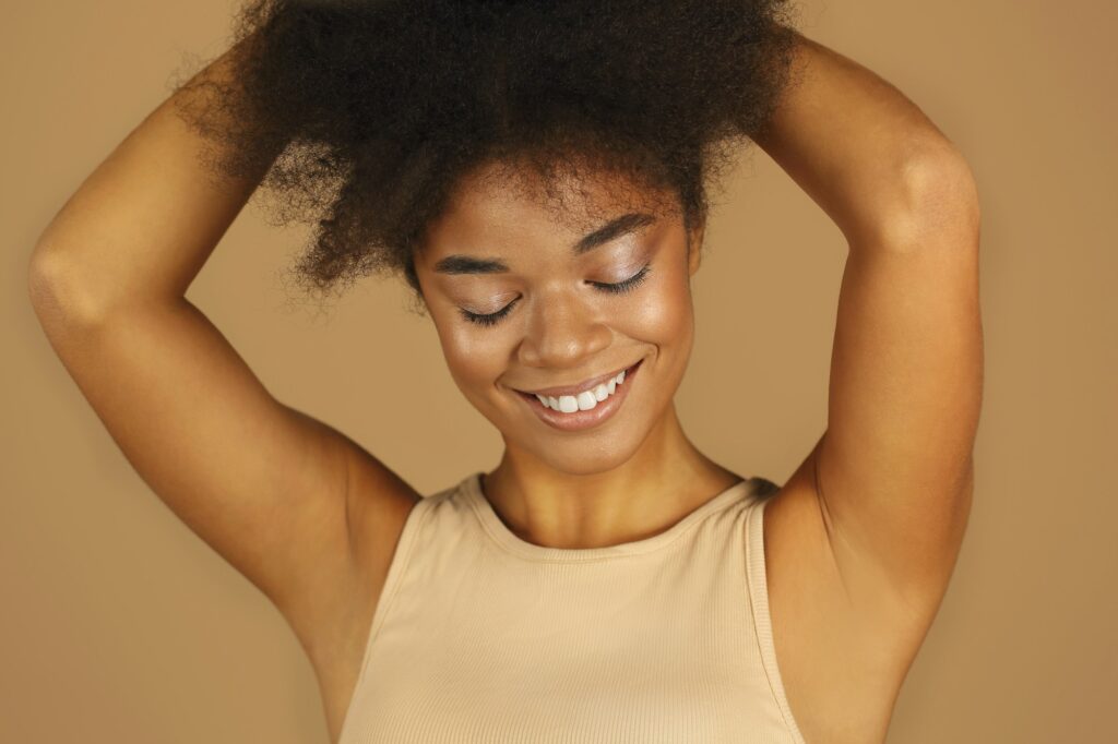 Young lovely african american woman with arms raised demonstrating smooth clean armpits without hair